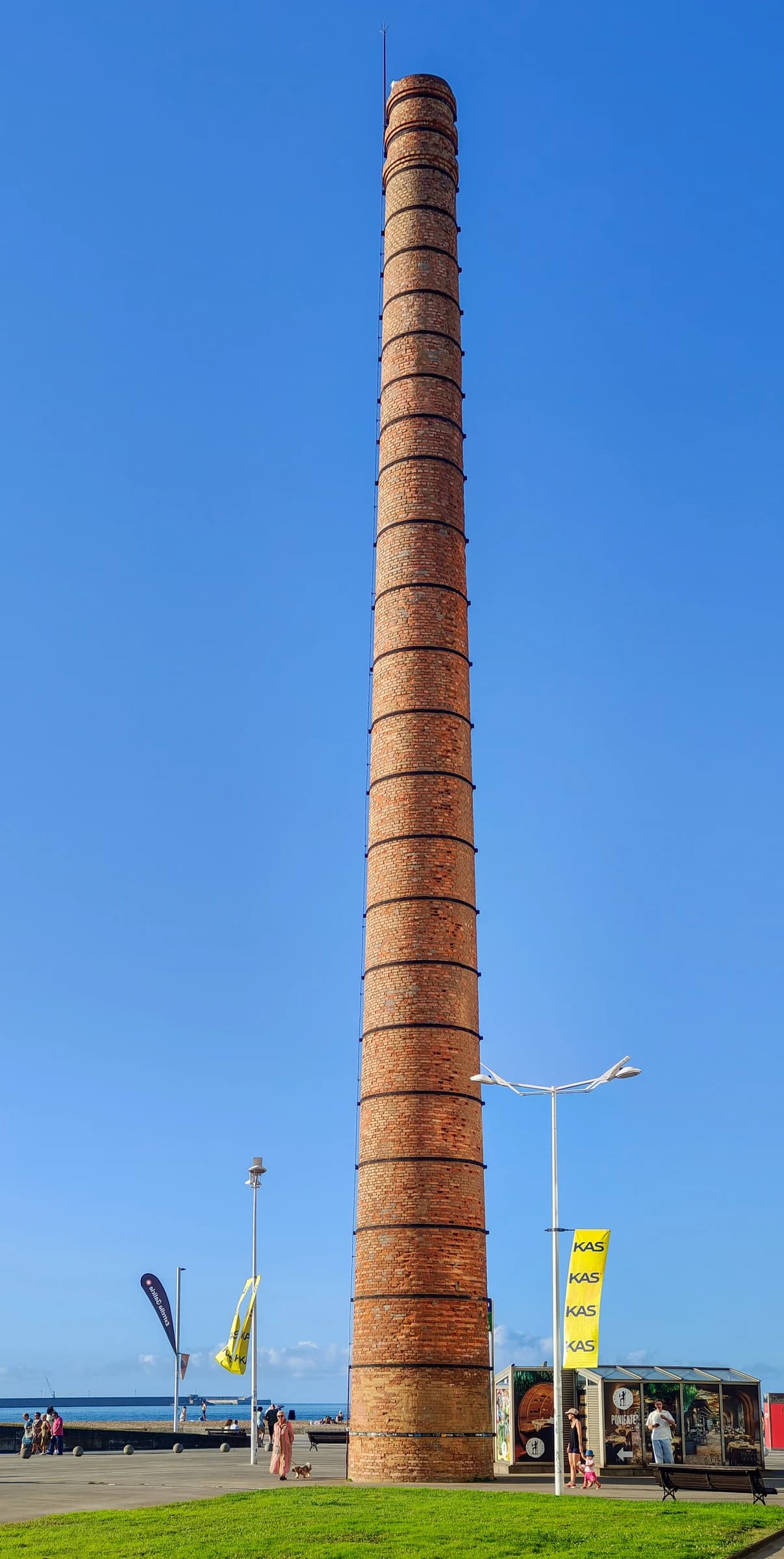 Tall brick industrial chimney at Poniente Beach in Gijón, Asturias, Spain.