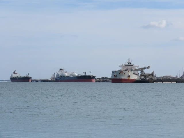 Oil products tanker, crude oil tanker, and bulk carrier docked at jetties at BP Oil Refinery.