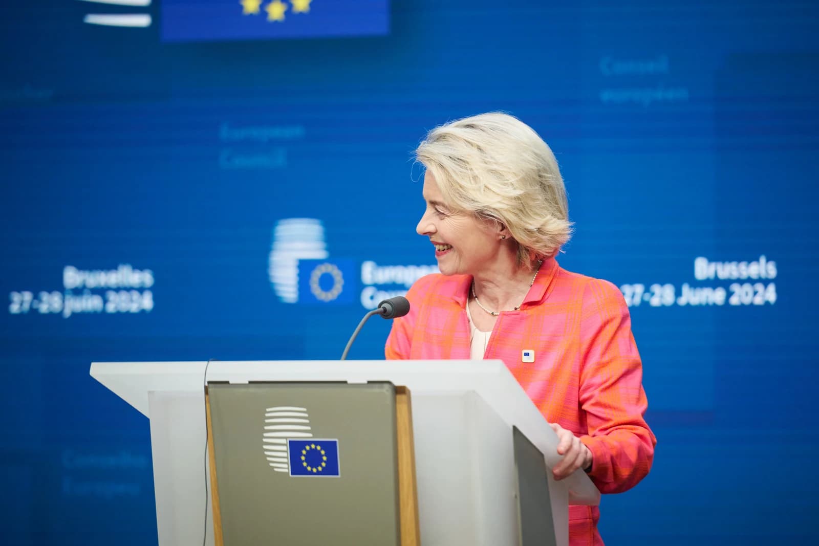 Ursula von der Leyen, President of the European Commission, smiling at a podium.