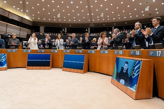 European Parliament members stand and applaud during a video address by Ukraine's President Volodymyr Zelenskyy.