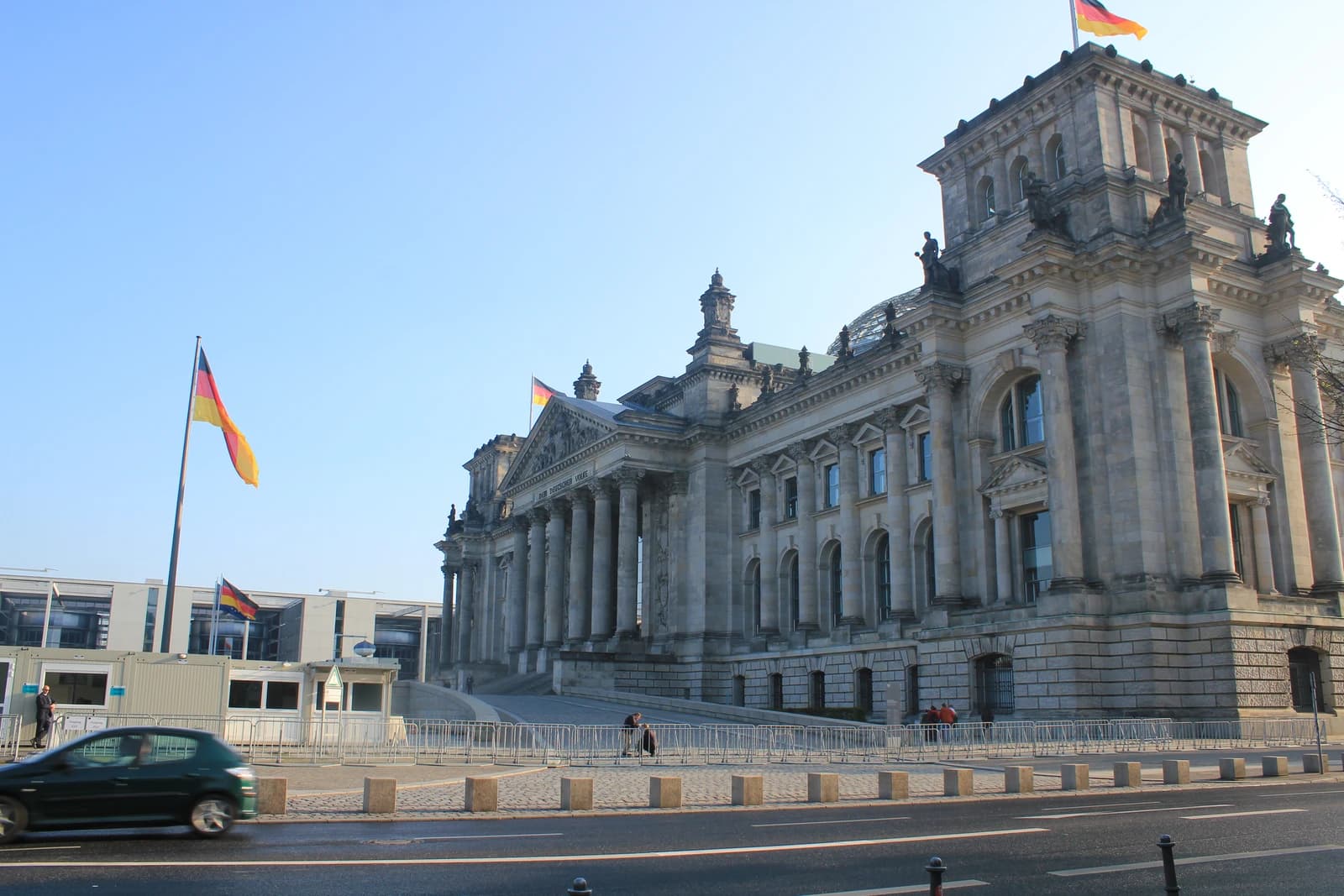 Exterior view of the Reichstag building in Berlin, Germany, with German flags flying.