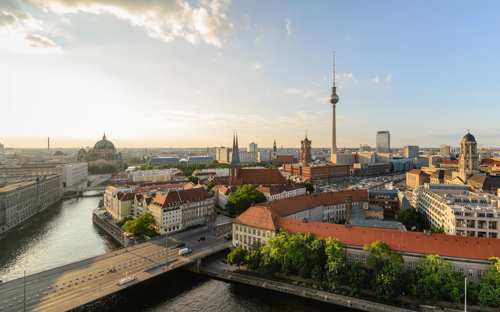 Aerial view of Berlin-Mitte cityscape at sunset with river, buildings, and Fernsehturm.