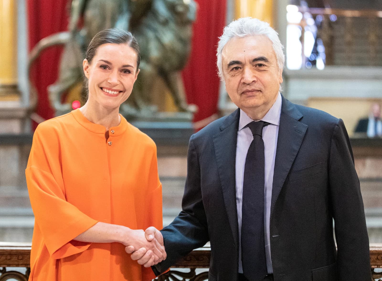 Finnish Prime Minister Sanna Marin and IEA Executive Director Fatih Birol shaking hands indoors.