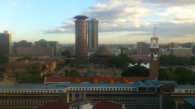Nairobi city skyline with prominent KICC and Times Tower buildings under a cloudy sky.