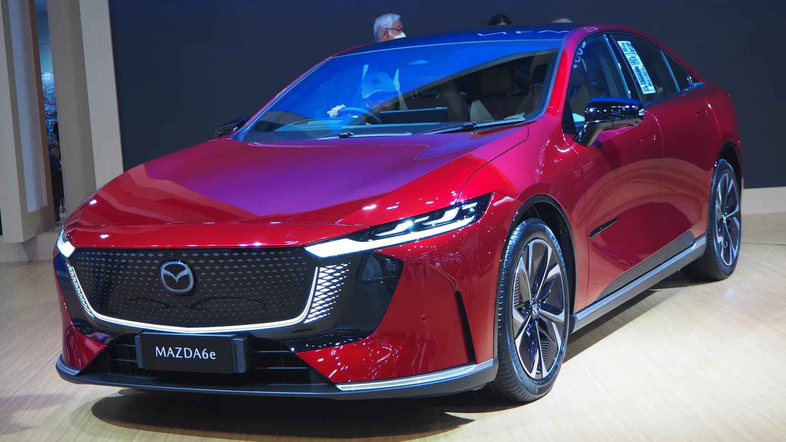 Red Mazda 6e electric vehicle displayed on a showroom floor.