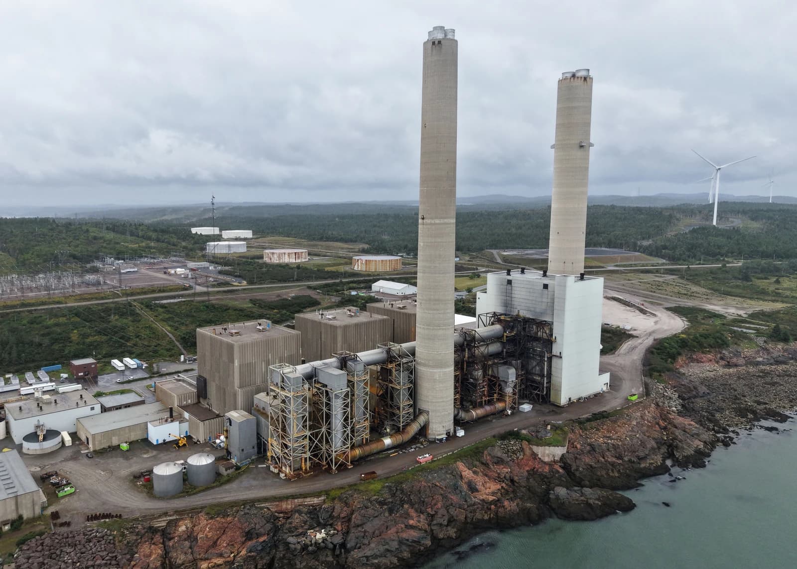 Aerial view of Coleson Cove Generating Station with large smokestacks on a rocky coast.