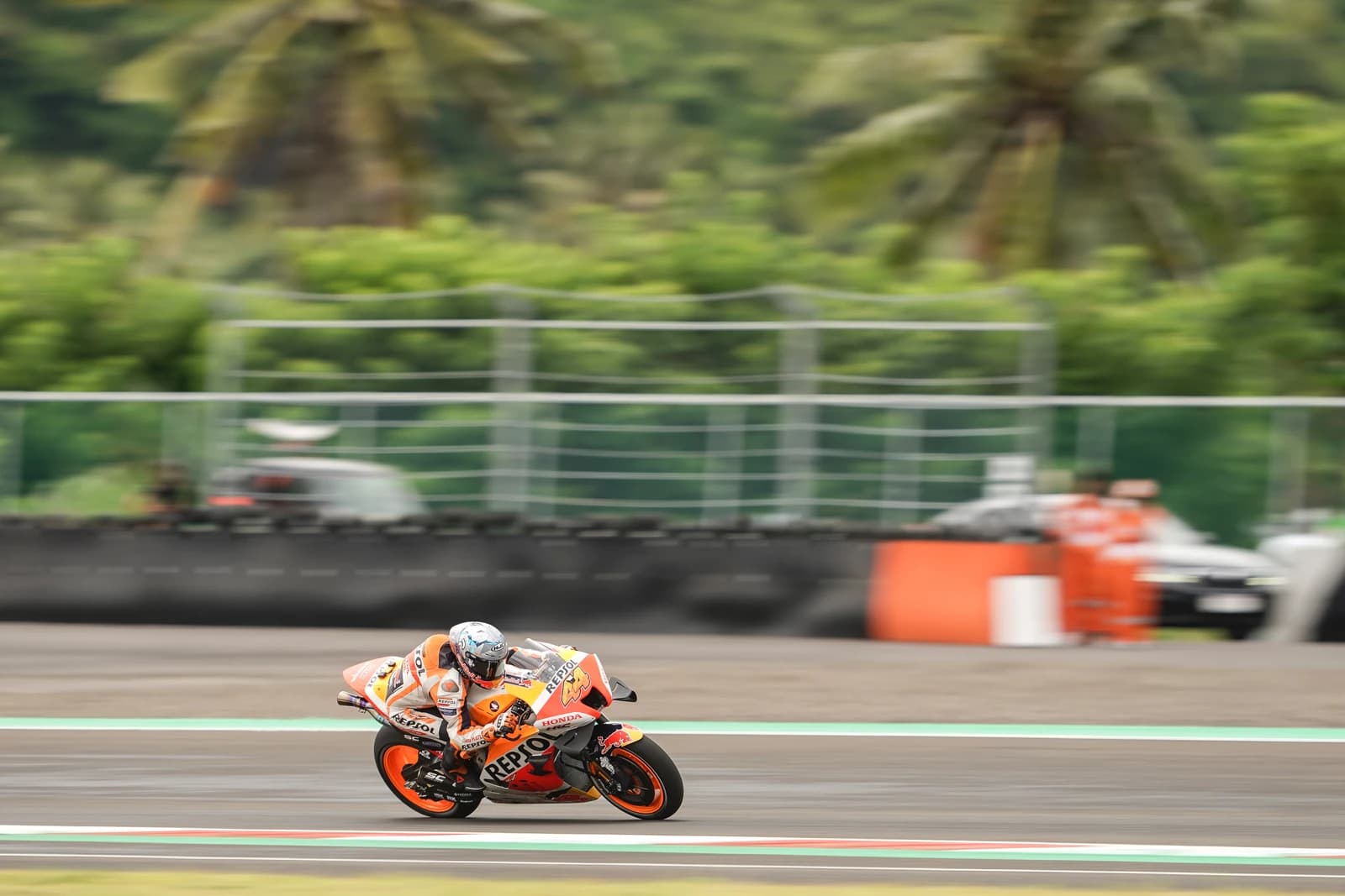 MotoGP rider Pol Espargaro on his orange and white Honda motorcycle racing on a track.