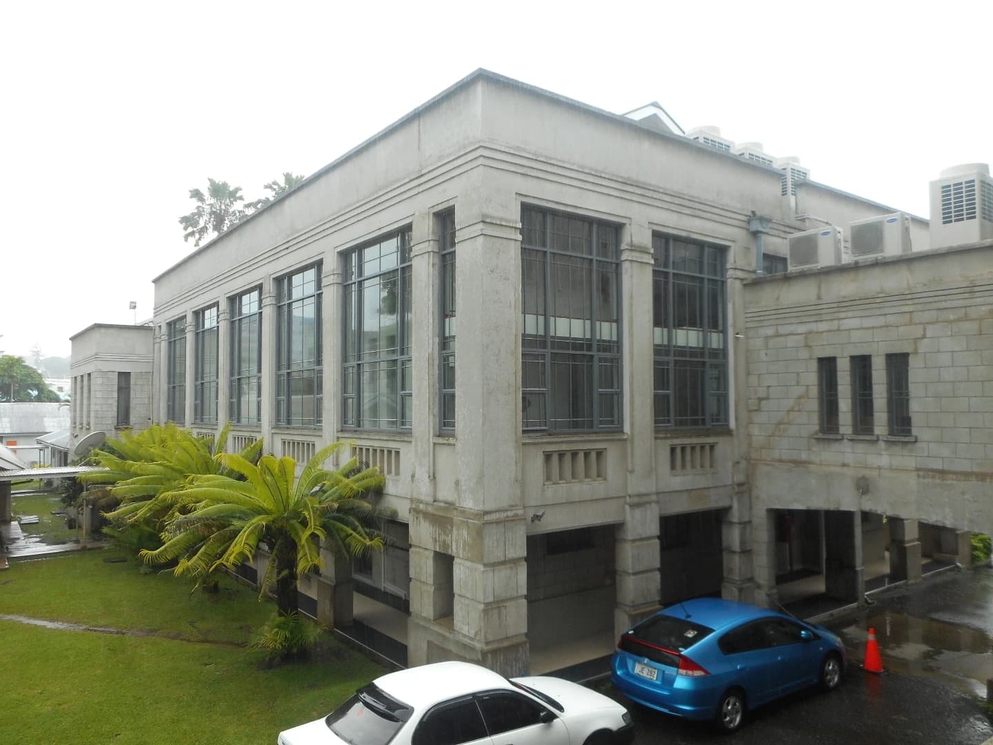 Exterior of the Fiji Parliament Chambers, a light-colored building with large windows.