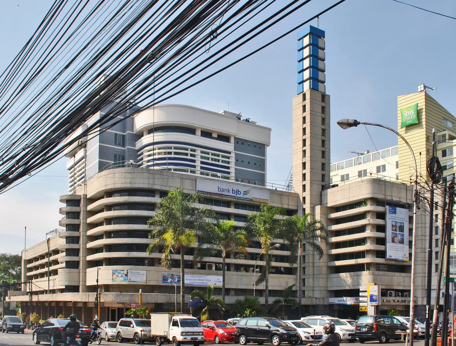 Bank BJB building with a multi-story parking structure and traffic on the street.