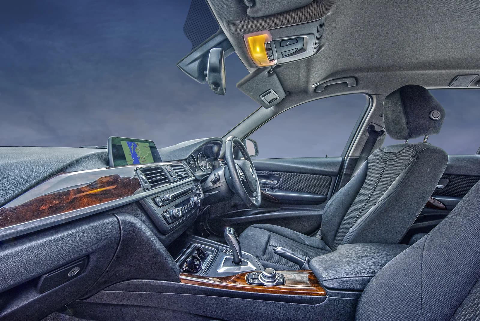 Driver's seat and dashboard of a BMW 3 Series car with a display screen.