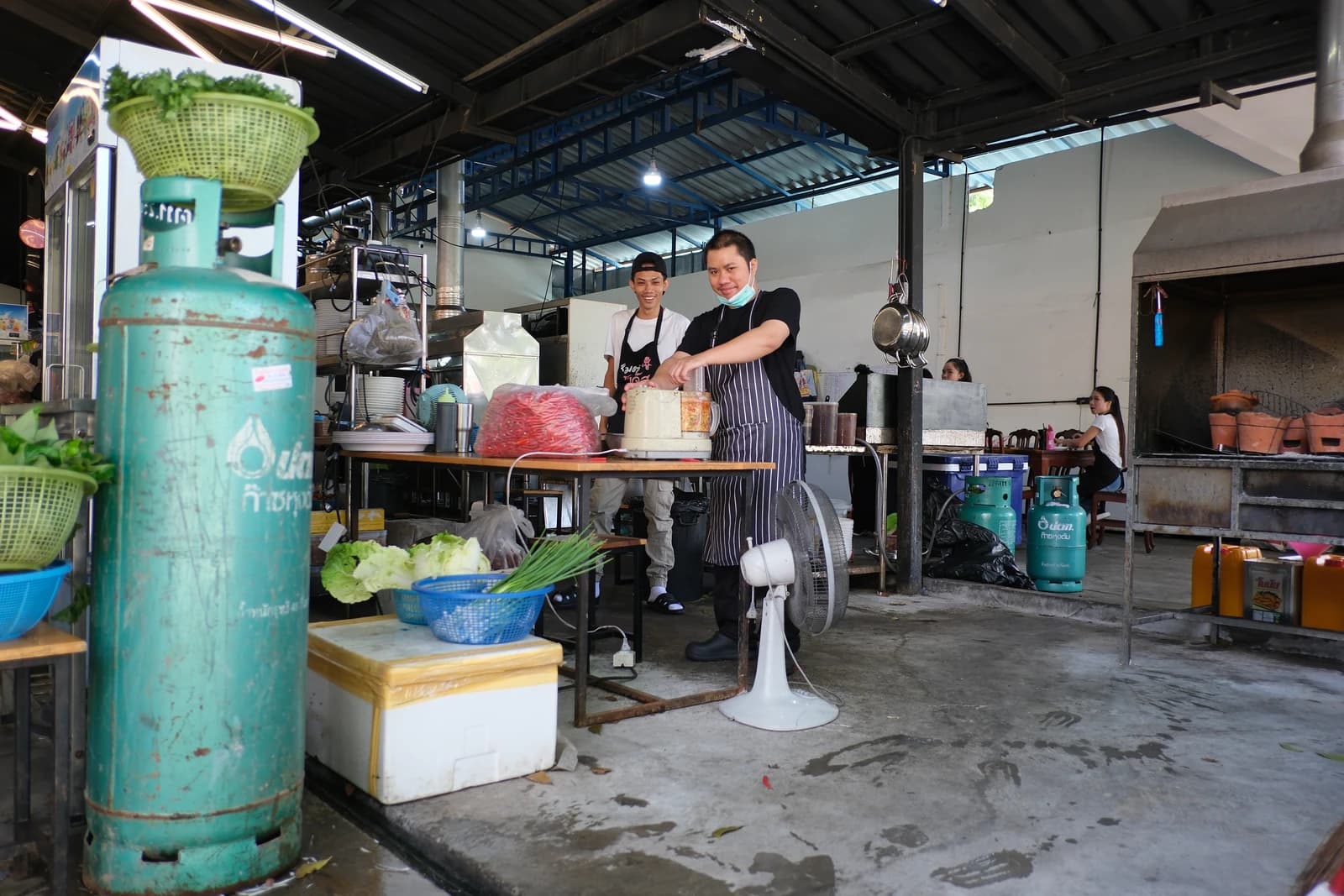 Two chefs preparing ingredients at an outdoor kitchen station.