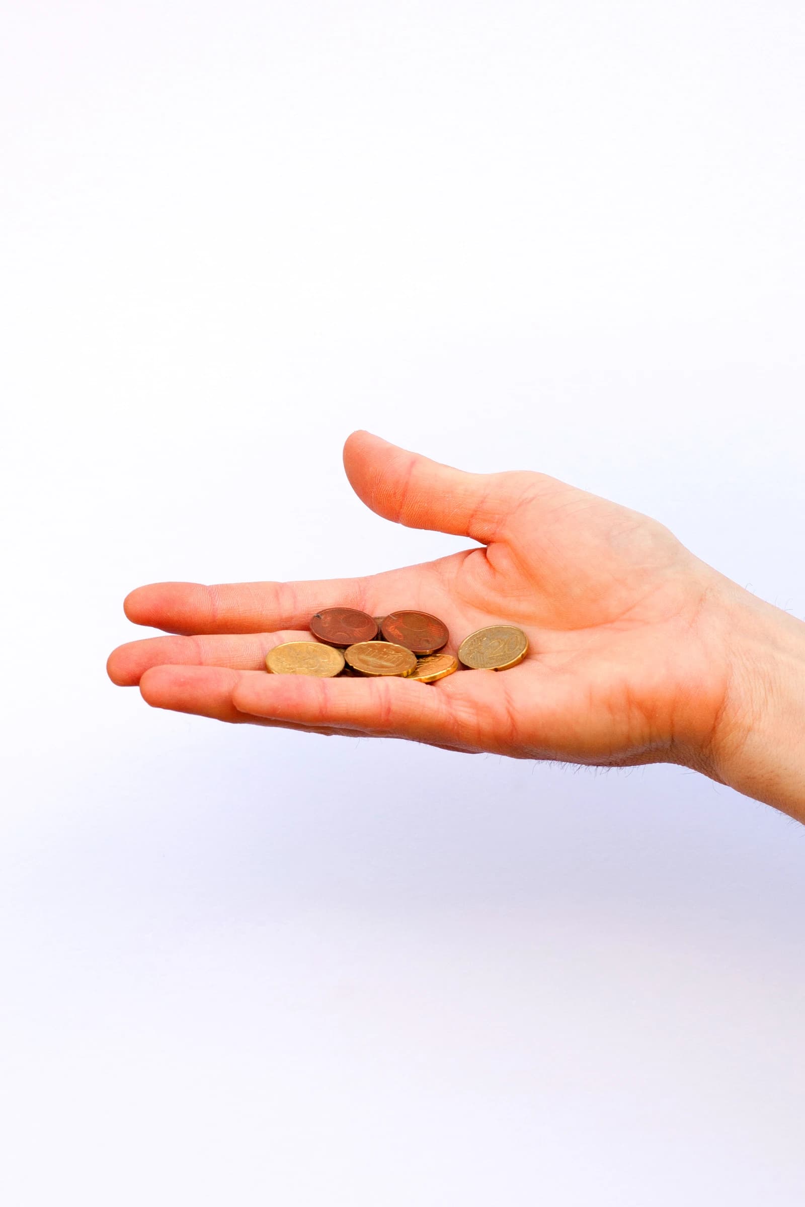 A hand holding several euro coins, including 1, 2, and 5 cent denominations.