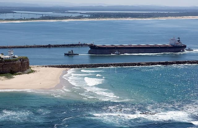 Bulk carrier ship entering Port Hunter, Newcastle, New South Wales, assisted by tugboats.
