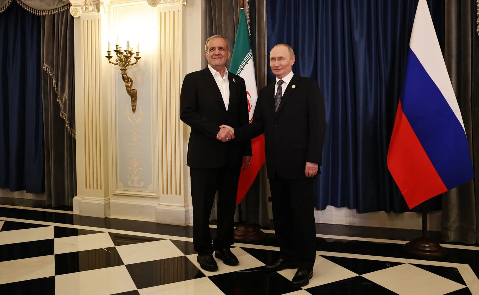 Iranian President Masoud Pezeshkian shakes hands with Russian President Vladimir Putin.