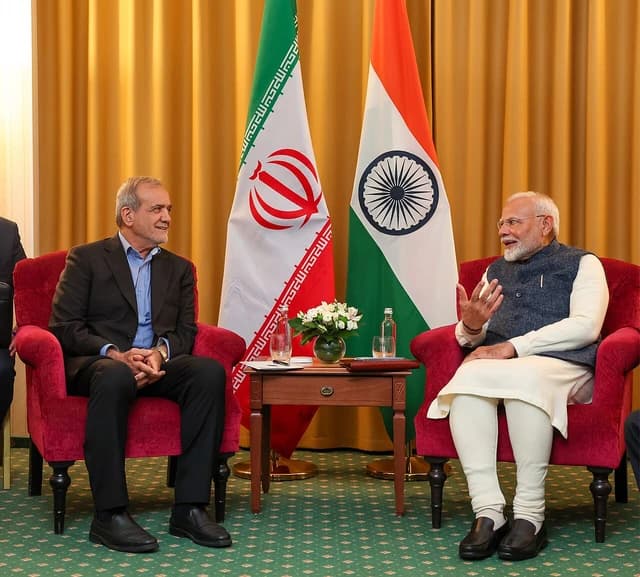 Iranian President Masoud Pezeshkian sits opposite another leader in a meeting.