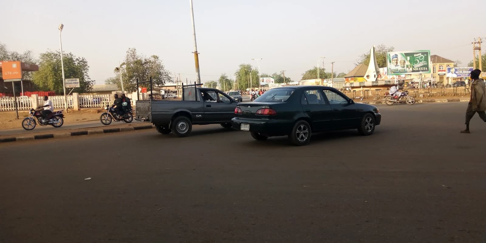 Truck and car driving on a road at a roundabout in Nigeria.