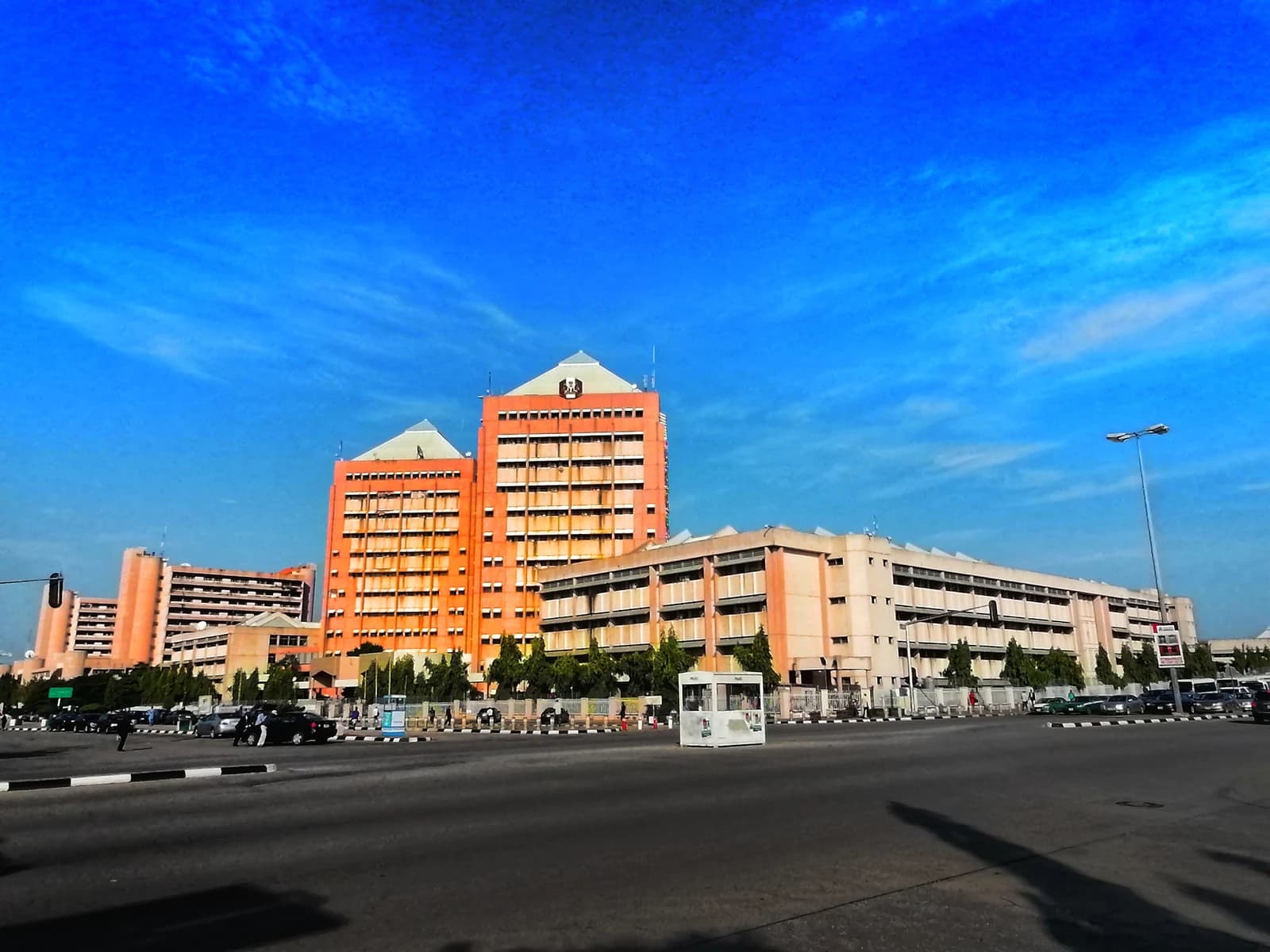 The Federal Secretariat Complex in Abuja, Nigeria, with a busy road in the foreground.