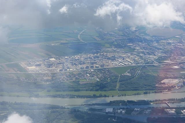 Aerial view of the OMV oil refinery complex in Schwechat, Austria, alongside a river.
