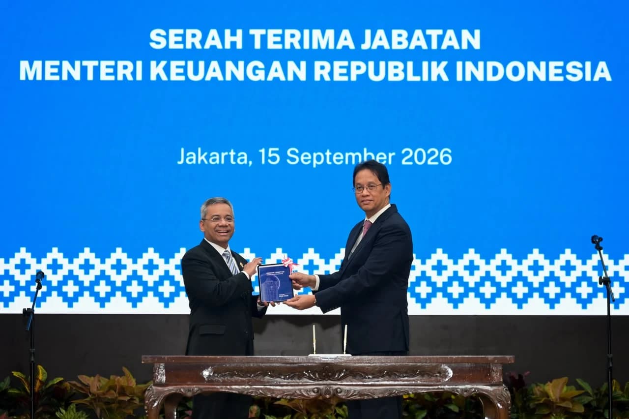 Two men, one possibly the Indonesian Minister of Finance, exchanging documents during a ceremony.