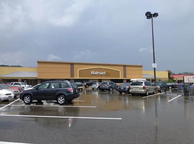Exterior of a Walmart store with a parking lot full of cars on an overcast day.