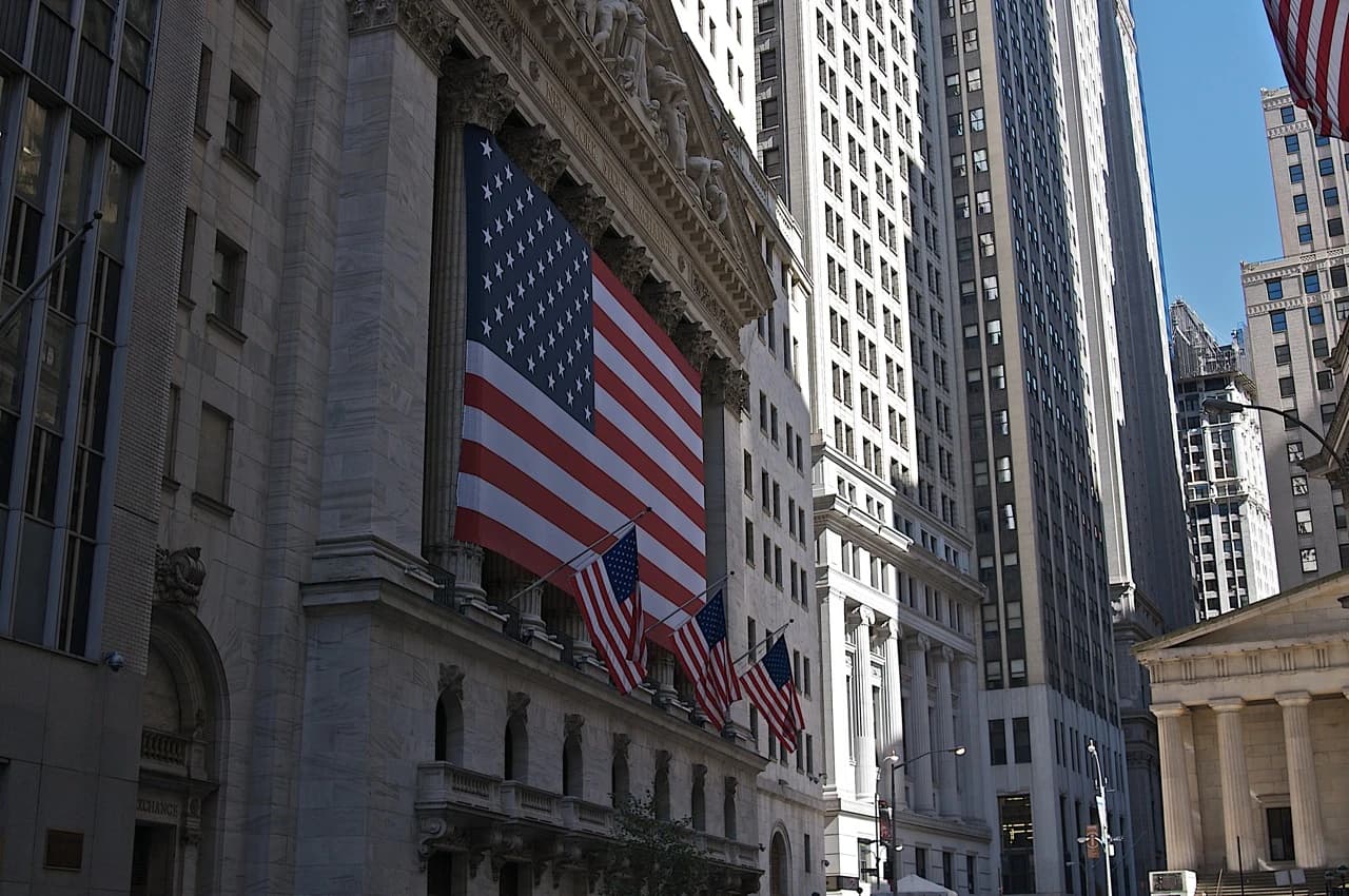 New York Stock Exchange building facade draped with a large American flag and smaller flags.