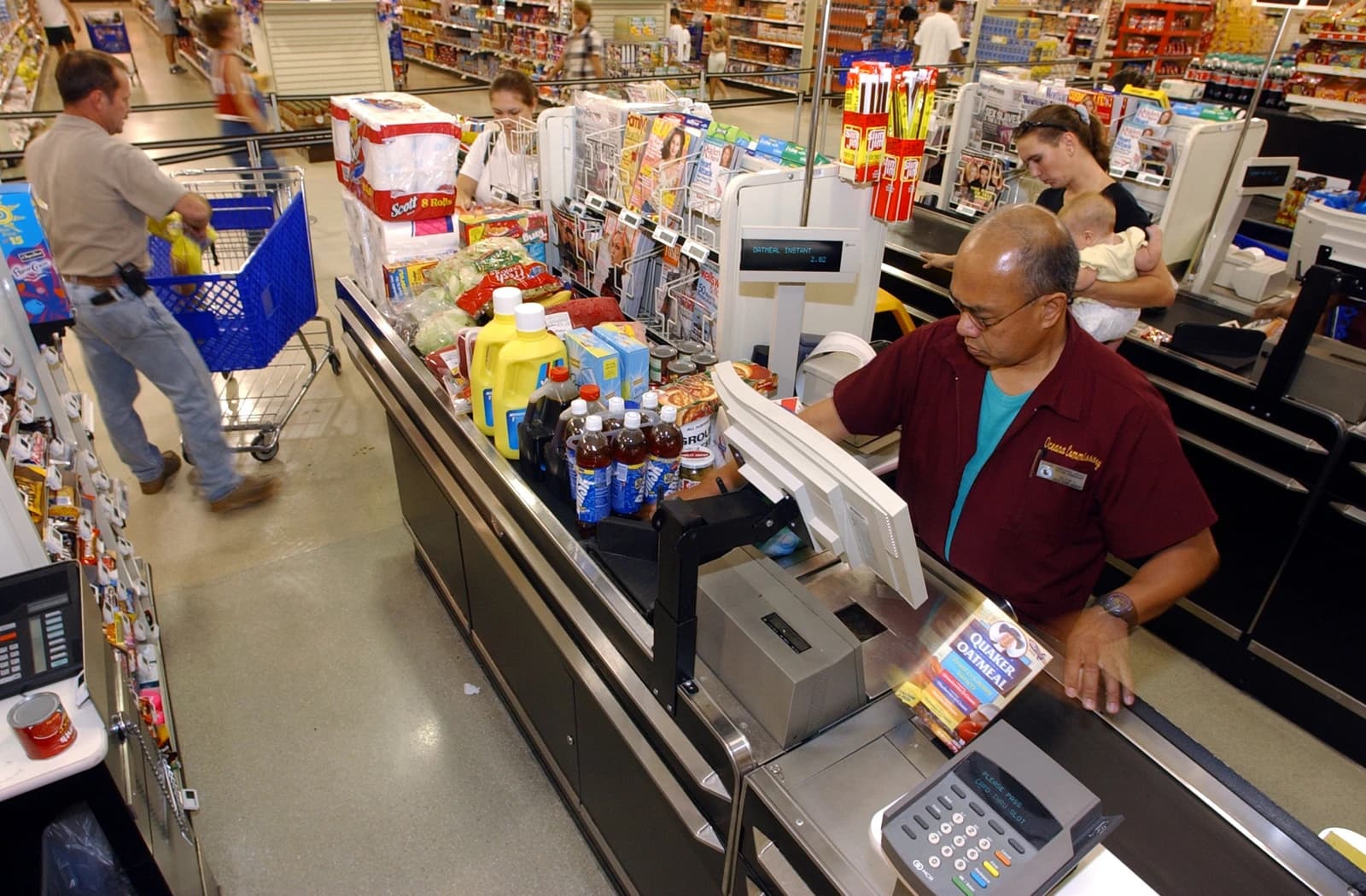 A cashier scans groceries at the Navy Commissary as a family unloads their cart.