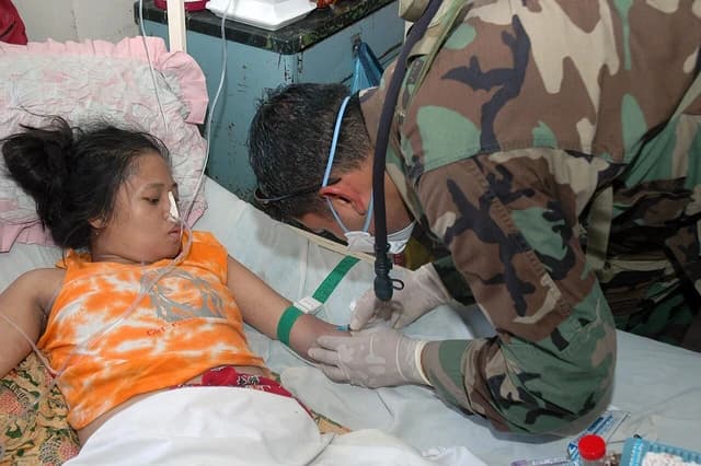 US Navy Hospital Corpsman Umair Iqbal draws blood from a patient at a medical center.