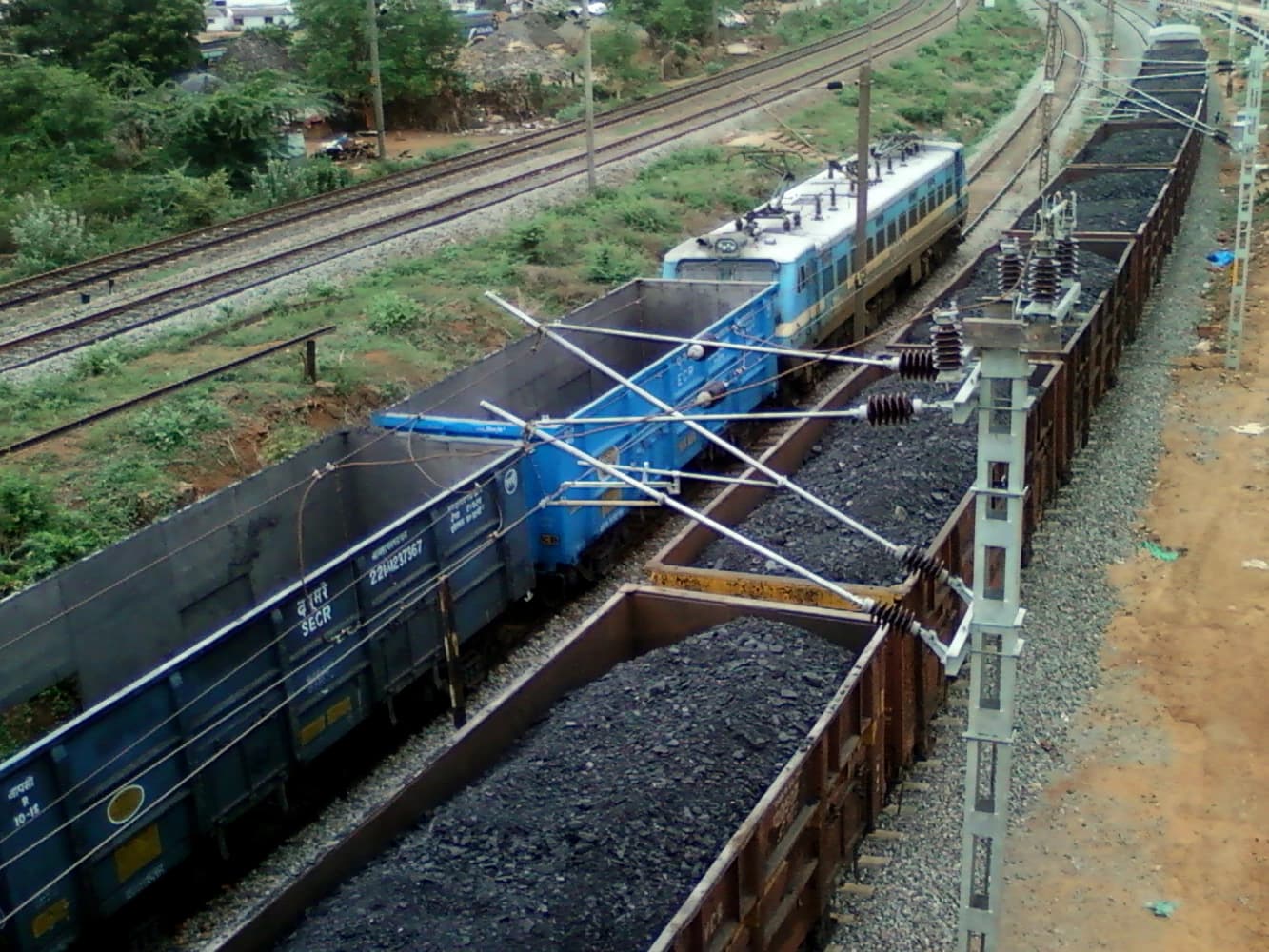 WAG-7 locomotive pulling open-top freight wagons filled with coal on tracks.