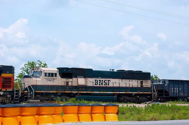 A BNSF locomotive 9807 pulling a train with an open-top hopper car.