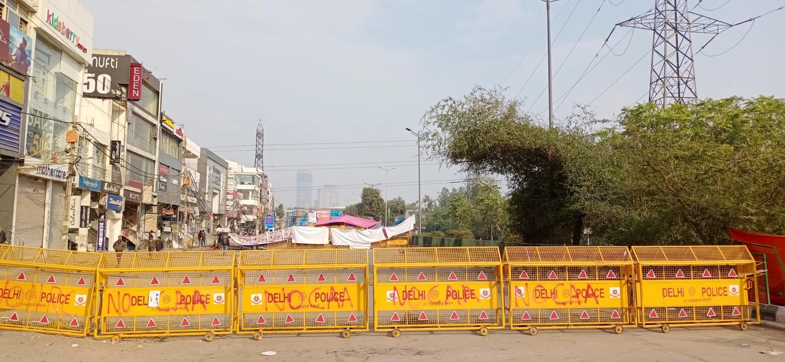 Yellow Delhi Police barricades with graffiti reading 'NO NRC CAA' block a road in New Delhi.