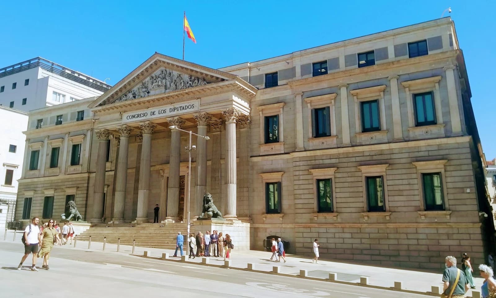 Exterior view of the Palacio de las Cortes building with the Spanish flag flying.