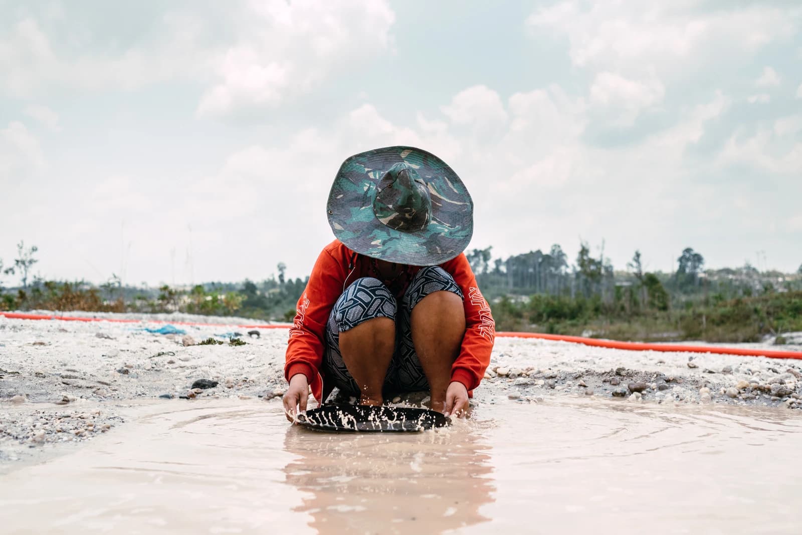 Female artisanal miner in Central Kalimantan panning for gold in water.