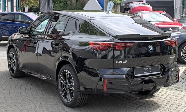 Black BMW iX2 xDrive30 electric vehicle viewed from the rear passenger side.