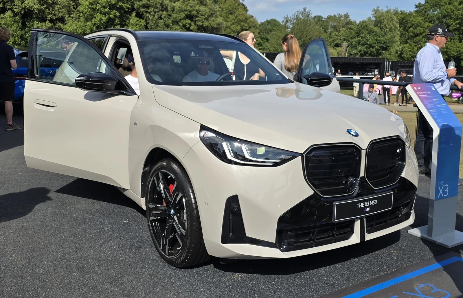 White 2024 BMW X3 M50 car parked outdoors with its doors open.