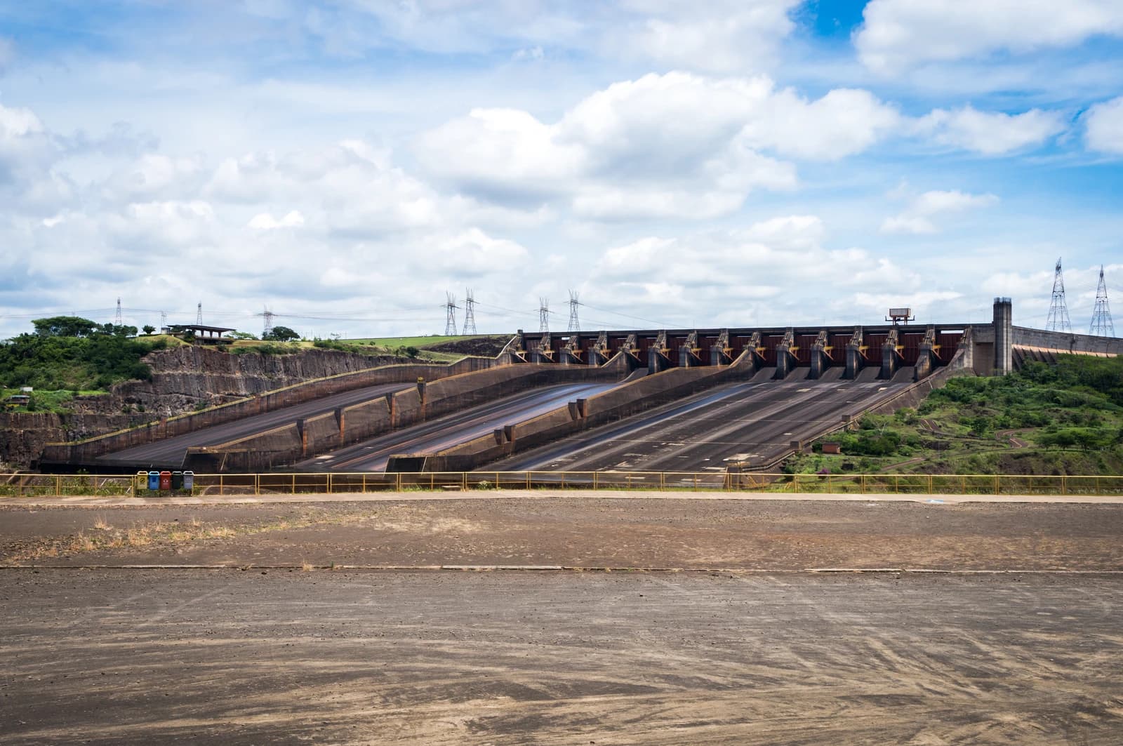 Itaipu hydroelectric dam spillway, large concrete structure with closed gates, under a partly cloudy sky.