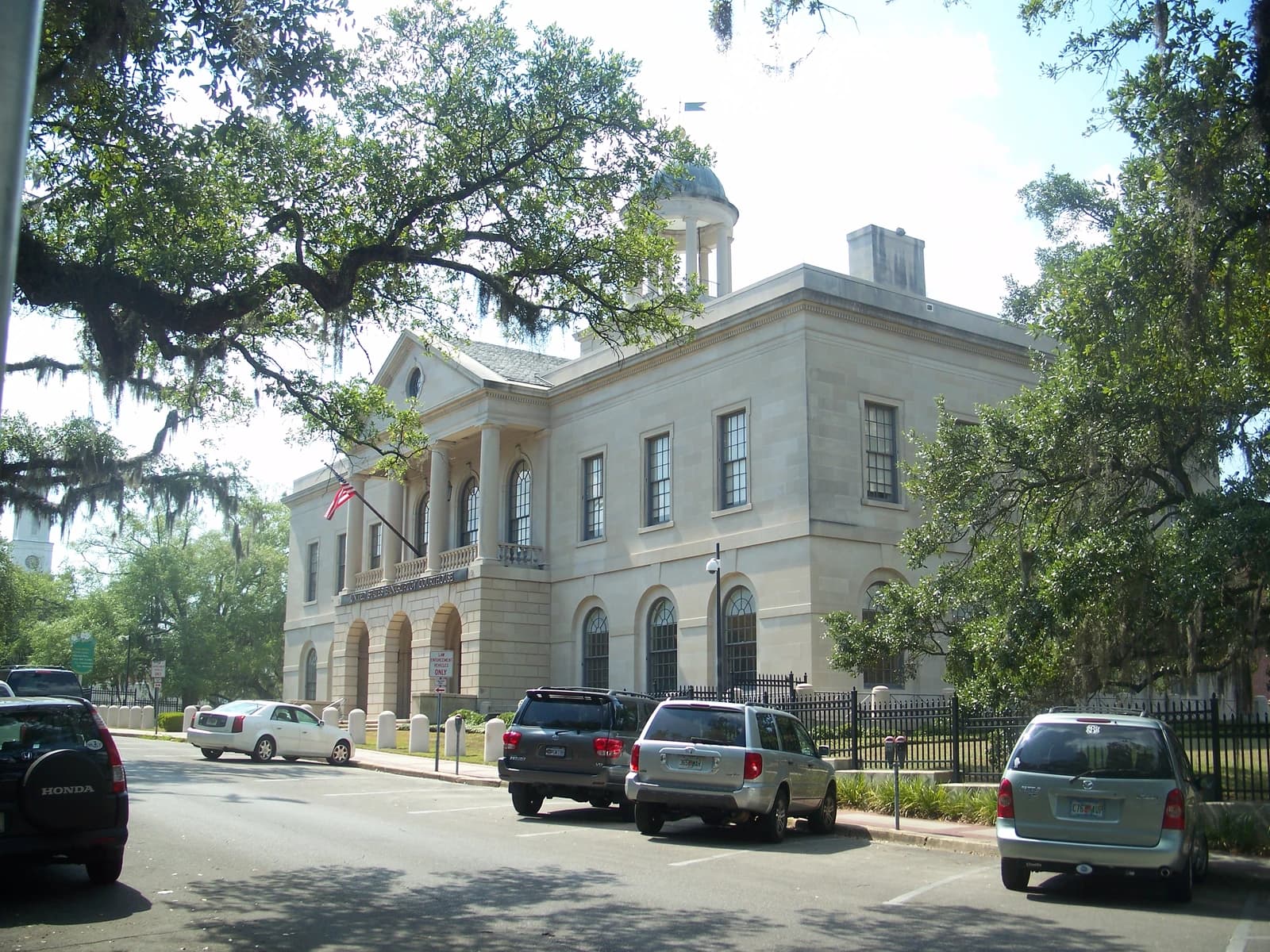 Tallahassee Bankruptcy Courthouse, a large stone building with columns and a dome, with cars parked nearby.