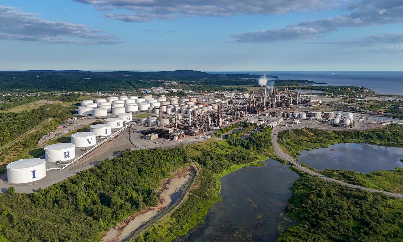 Aerial view of the large Irving Oil Refinery complex with storage tanks and processing units.