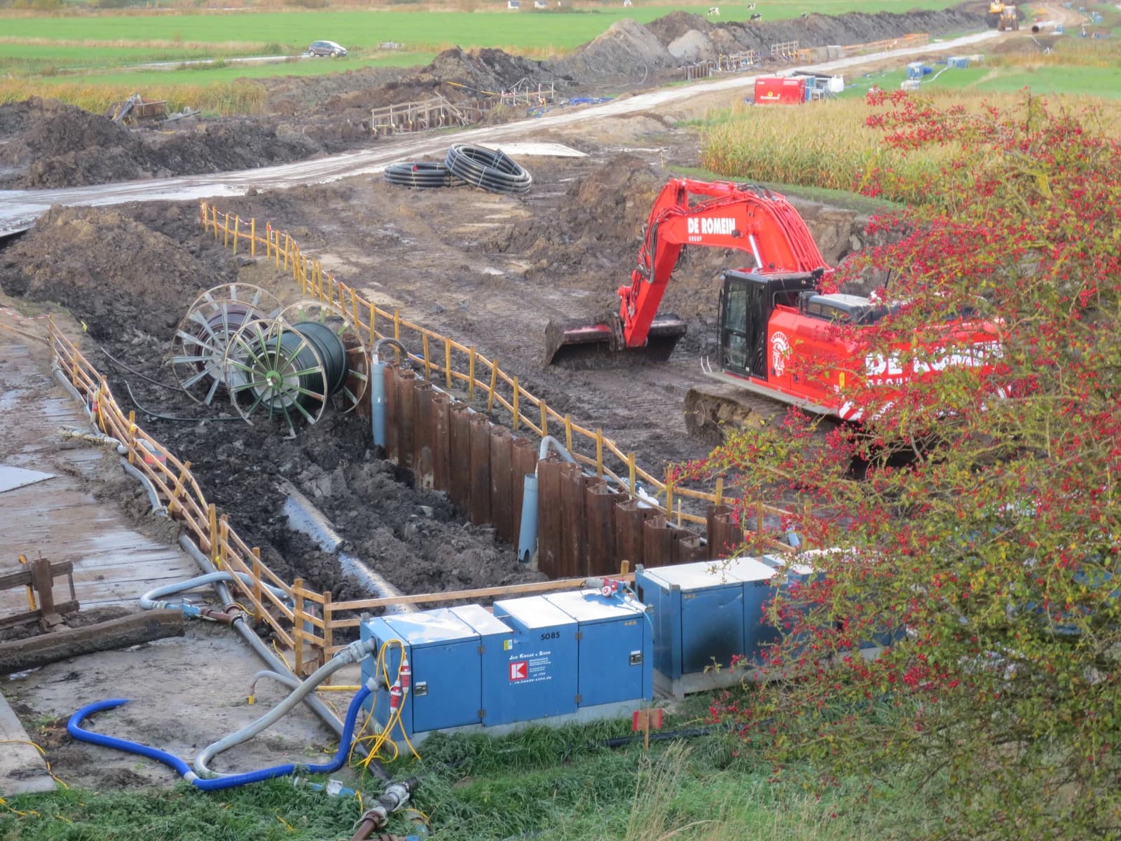 An excavator and spools of pipe at an LNG pipeline construction site.
