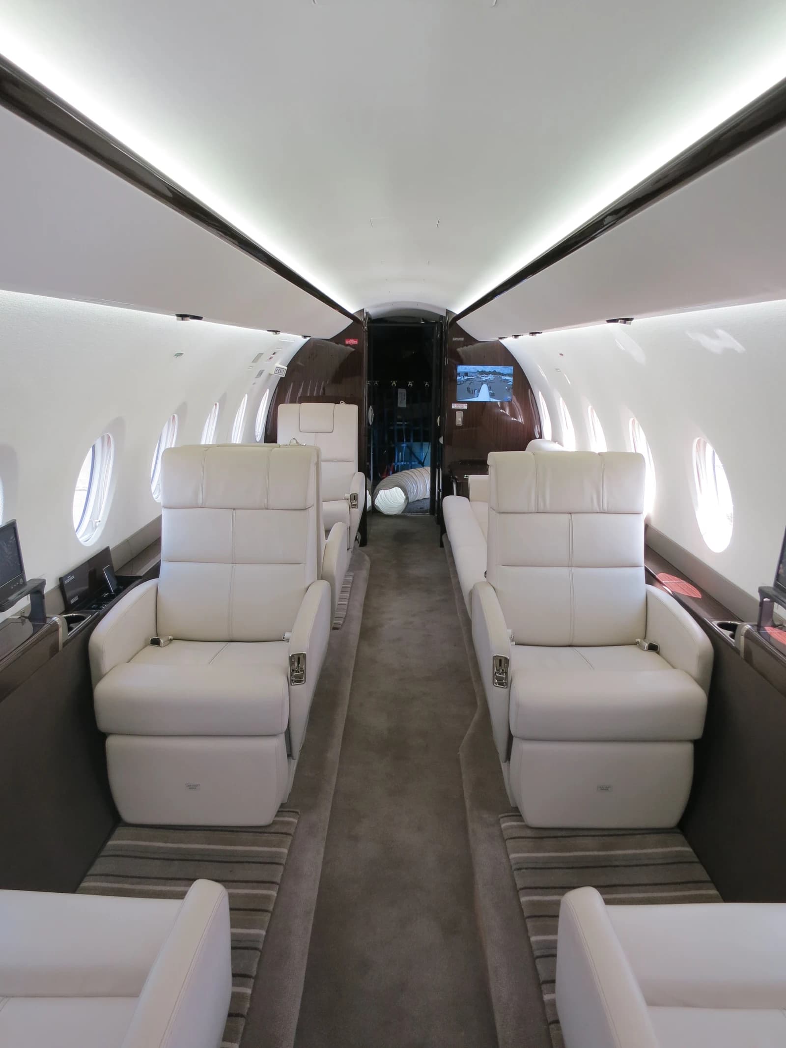An interior view of a Gulfstream G280 private jet cabin with white leather seats.