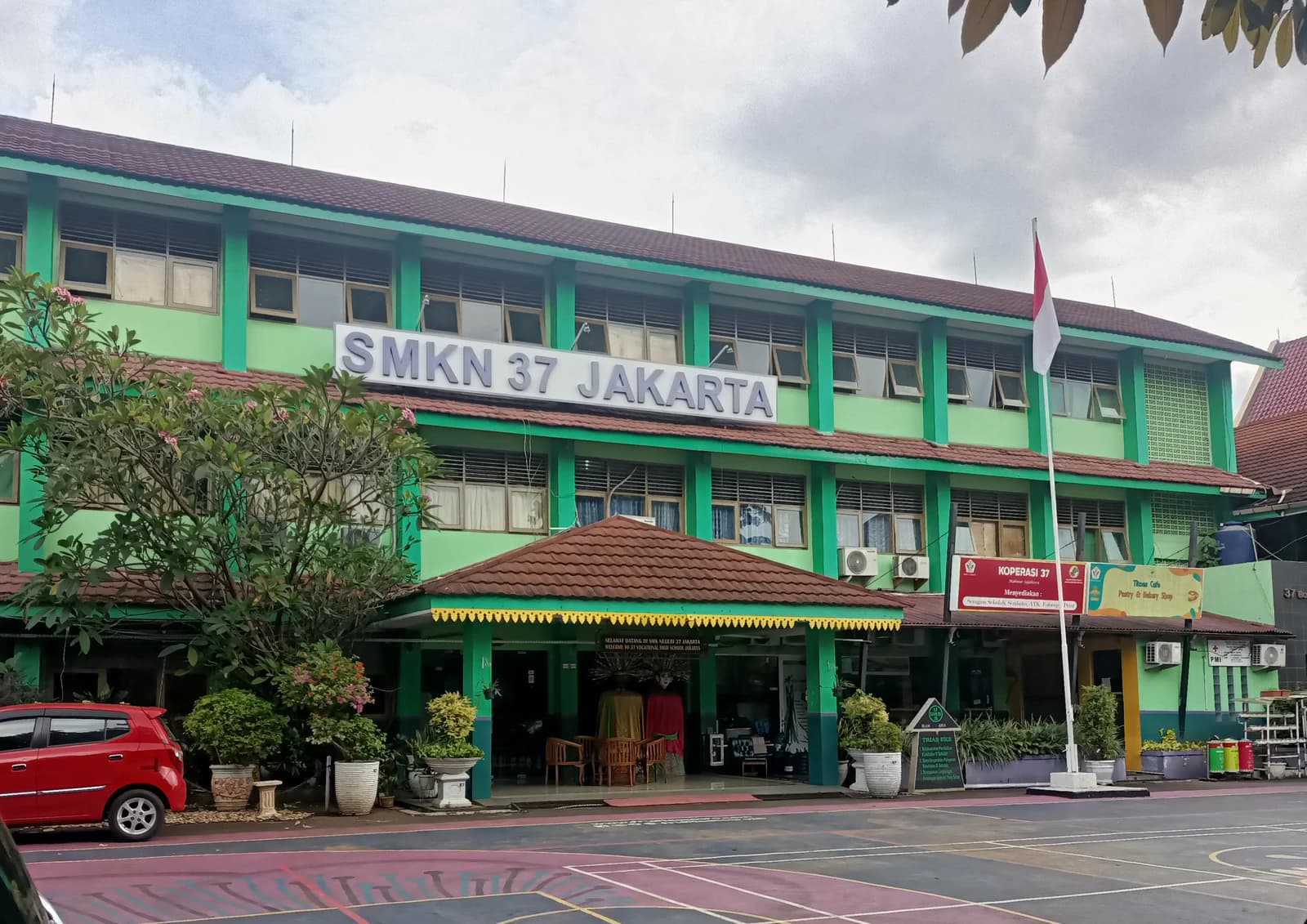 Exterior view of the SMKN 37 Jakarta school building, showing its green facade and entrance.