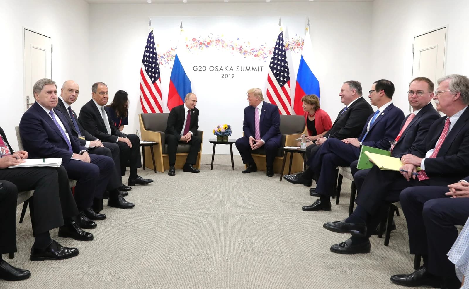 US and Russian presidents, Vladimir Putin and Donald Trump, face each other at a large meeting.