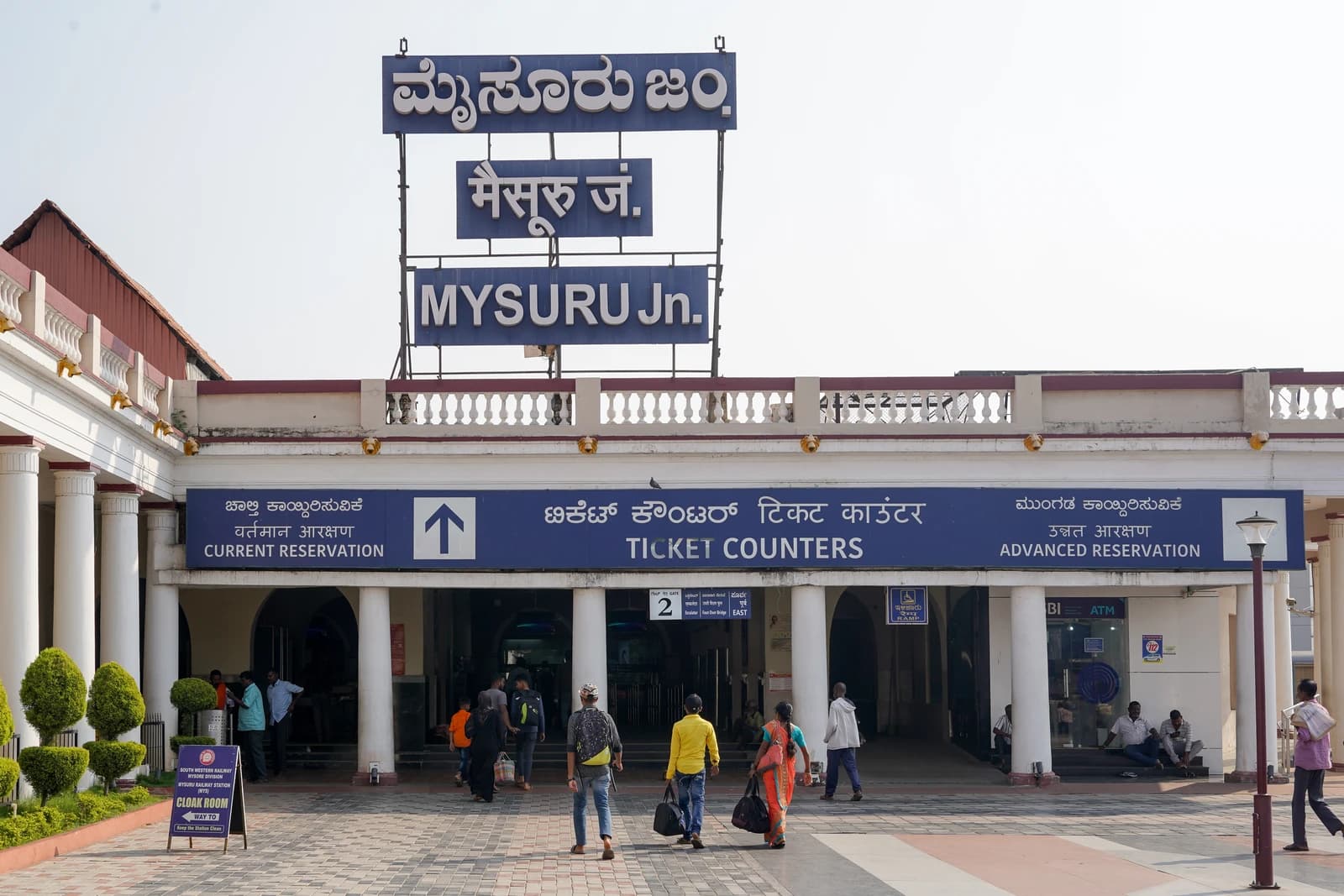 People walking towards ticket counters at Mysuru Junction railway station in India.