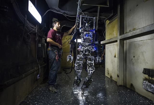 An engineer stands next to the SAFFiR firefighting robot prototype.