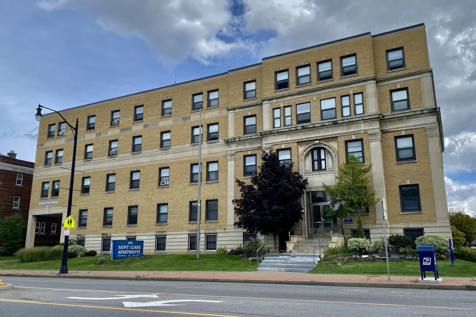 Exterior view of Saint Clare Apartments, a multi-story brick building with many windows.