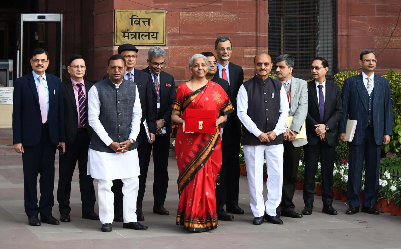 Smt. Nirmala Sitharaman, Union Minister for Finance, holding a red budget document, surrounded by officials.
