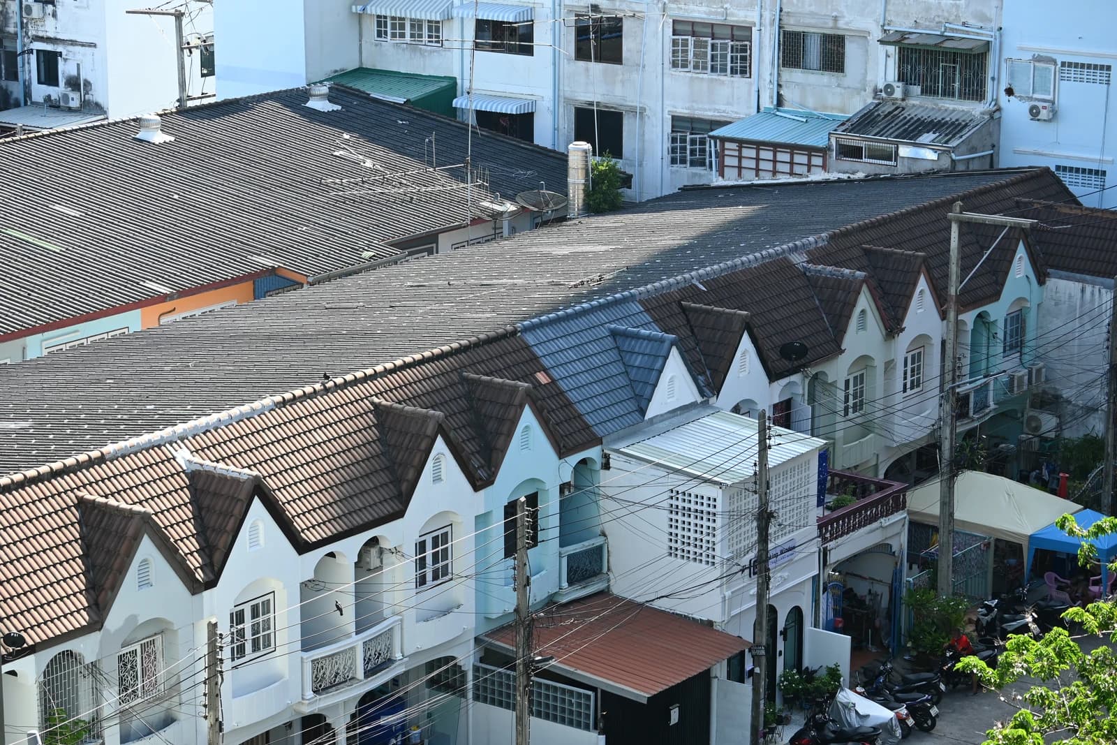 A row of connected townhouses with peaked roofs lines a quiet street.