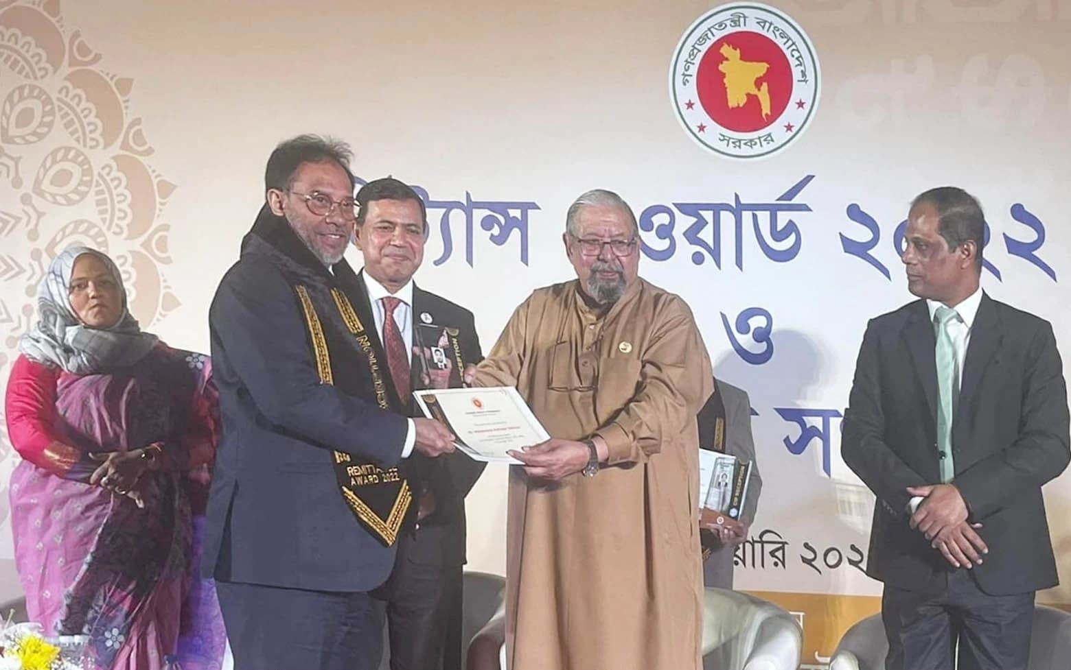 Minister Imran Ahmad presents a Remittance Award 2022 certificate to an expatriate man.