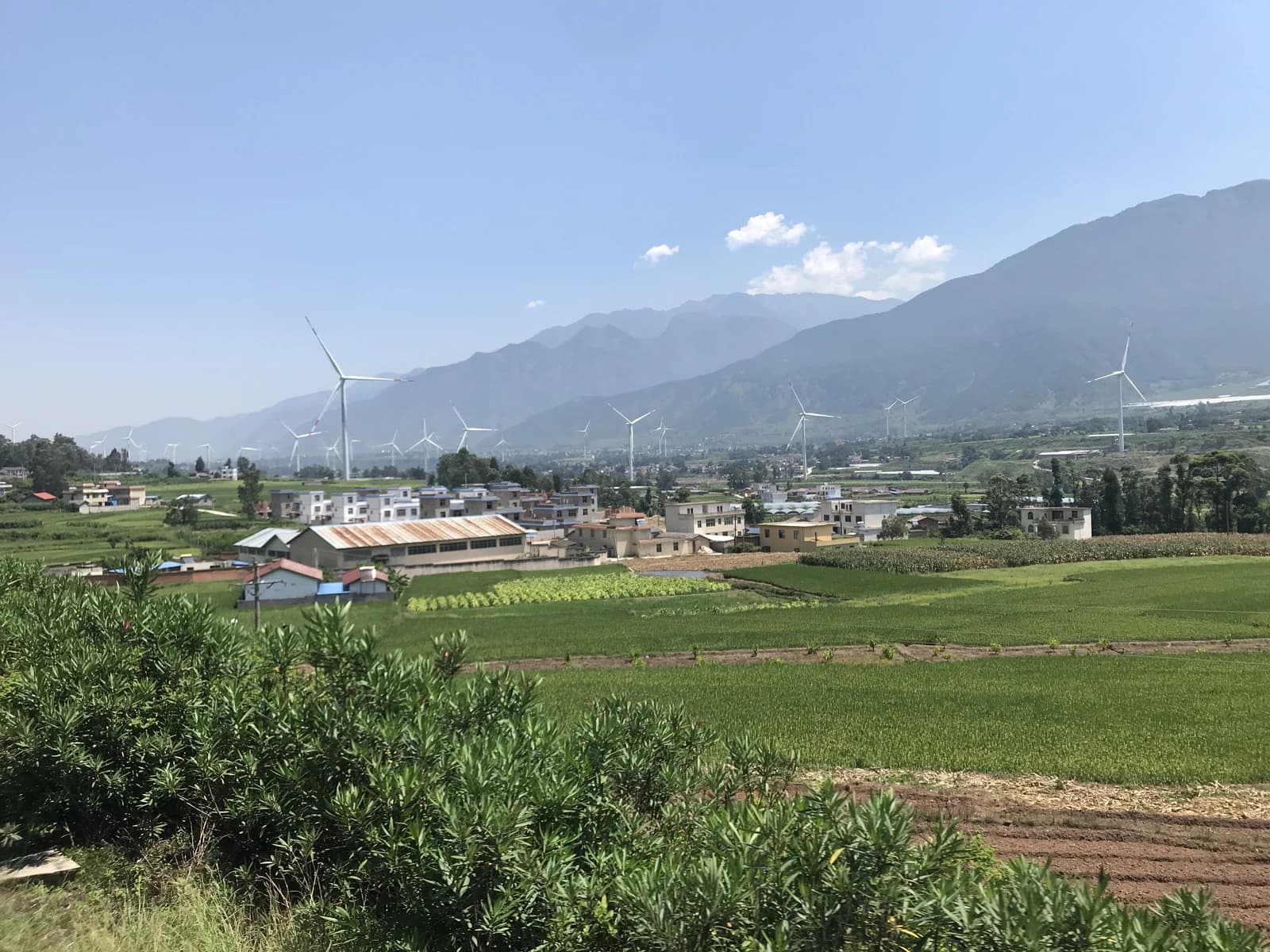 Wind turbines in Dechang Wind Farm in China, with Huangjiaba Village and mountains.