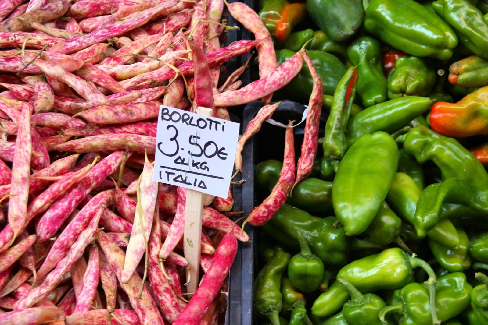 Borlotti beans and green peppers displayed for sale at an Italian market.