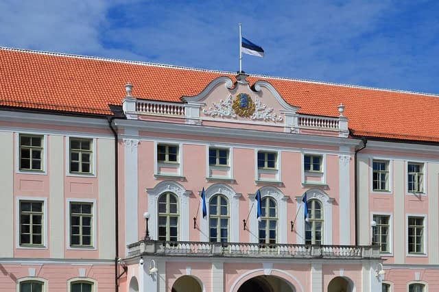 The pink facade of Toompea Castle, home to the Parliament of Estonia, with an Estonian flag.